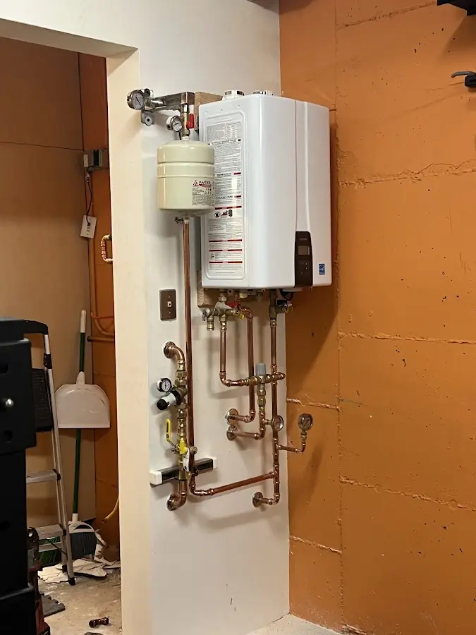Plumbing technician inspecting water heater connections in East Fallowfield
